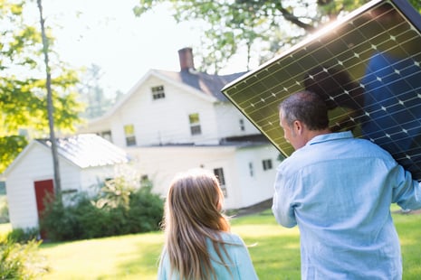 a-man-carrying-a-solar-panel-towards-a-building-un-2023-11-27-04-55-32-utc